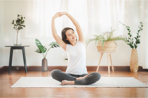 明るい部屋で気持ちよく伸びをしている女性