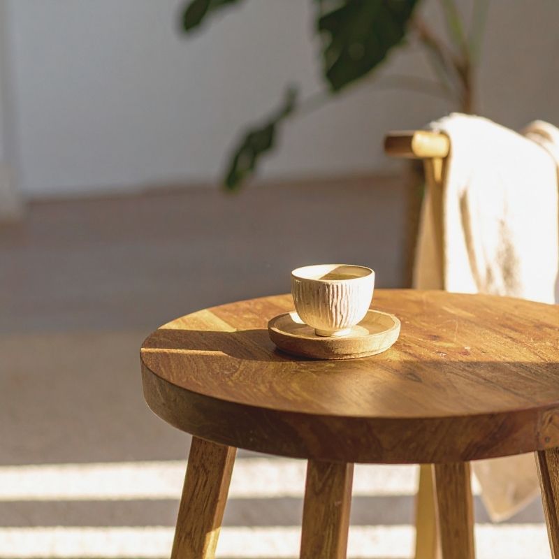 コーヒーカップが置かれた木製の丸テーブルと椅子のあるリビング風景